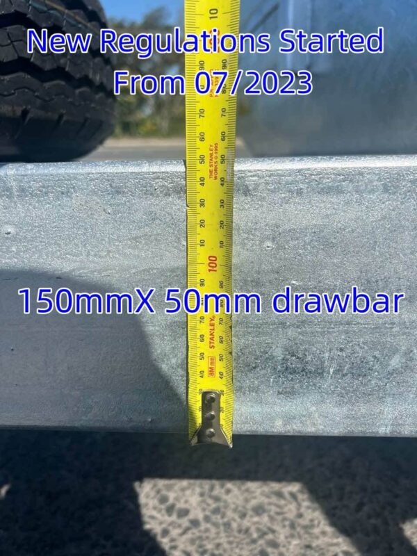 A yellow measuring tape displays measurements on a metal surface, featuring the text New Regulations Started From 07/2023 and 150mm X 50mm drawbar, with a tire partially visible. This image highlights the Premium 12x6 Dual Axle Heavy Duty Tandem Trailer - 3500KG ATM For Sale.