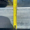 A yellow tape measure shows about 100 cm in height on the metal surface of the 8×5 Dual Axle Hydraulic Tipper Tandem Box Trailer - 3500KG ATM With Ramp Holders. A tire appears in the upper left corner of the image.