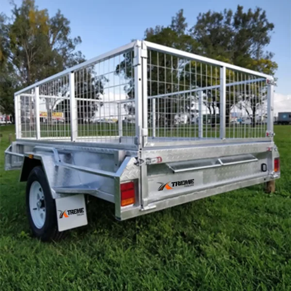 A 6x4 Single Axle Box Trailer ATM 750KG with mesh sides is parked on grass, featuring a jockey wheel and branded Xtreme on the side and mudguard. Trees and a cloudy sky form the background.