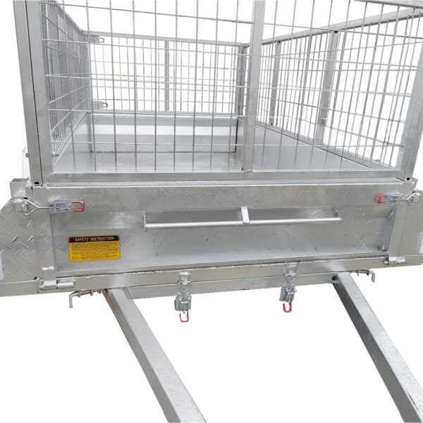 A close-up of the 8x5 Single Axle Box Trailer ATM 750KG With Jockey Wheel shows its grated metal floor and sides, sturdy supports, safety instruction labels, and locking mechanisms at the base.