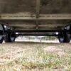 A close-up view shows the metal frame and wheels of the Premium 8x6 Dual Axle Heavy Duty Tandem Trailer (2000KG ATM), positioned on short grass outdoors.