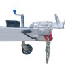 A trailer hitch with a metal frame, a silver coupler, and a red lock. A chain hangs from the hitch. A small wheel is attached for maneuverability. A blue-handled crank is visible on top.