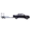 A black pickup truck is towing a silver utility trailer with two axles and ramps. The trailer appears empty, and the truck is viewed in profile from the side against a plain white background.