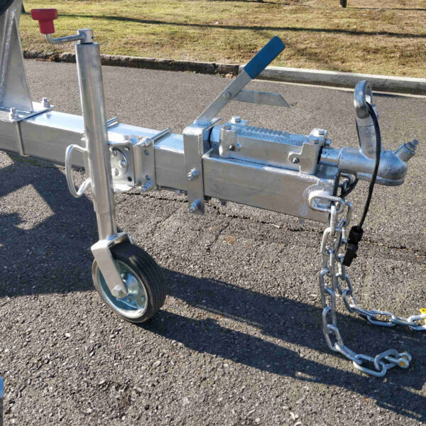 Close-up of a 6.2m galvanized boat trailer with 2000kg ATM on a sunny day; the metal hitch is attached to a wheel and safety chain, resting on asphalt with grass in the background—ideal for boats 5.7m-6.2m (18.7-20.3ft).