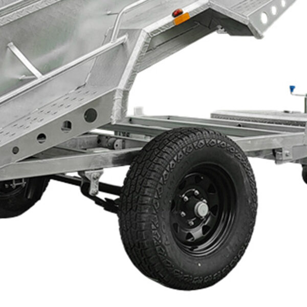 Close-up of the undercarriage on the 8x5 Hydraulic Tipper Single Axle Box Trailer ATM 1800kg, showing a black tire, chassis section, and angled support beams. The metal trailer is tipped to display its hydraulic mechanism.