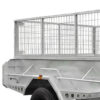 A close-up of the 8x5 Hydraulic Tipper Single Axle Box Trailer ATM 1800kg features metal mesh sides, a sturdy angular frame, and a large black tire, all set against a clean white background.