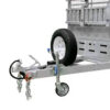 Close-up of the Premium 10x7 Galvanized Flat Top Trailer with 4500KGS ATM, featuring safety chains attached to the trailer hitch, a jack with a wheel, a spare tire mounted on the sturdy metal frame, and part of the trailer’s side railings in view.