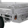 Close-up of the rear corner of the Premium 10x7 Galvanized Flat Top Trailer with 4500KGS ATM (Pre-order), featuring its tailgate, latch mechanisms, wheel, and a diamond-plate toolbox with an integrated rear light.
