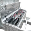 Mounted on a metal frame, the Premium 12×7 Hydraulic 3-Way Tipper Galvanised Flat Top Trailer 4500kg ATM (Pre-order) features an open metal toolbox with a diamond plate pattern that reveals electrical components inside, including a black battery and red and black wires. The toolbox is equipped with a latch and support struts.