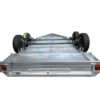 A view from underneath the Premium 8x5 Dual Axle Heavy Duty Tandem Trailer (425mm High Sides, 3500KG ATM) shows its sturdy metal frame, two axles with black tires, and tail lights mounted at the rear.
