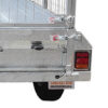 Close-up of the back corner of the Premium 8x5 Dual Axle Heavy Duty Tandem Trailer (425mm High Sides, 3500KG ATM), showing its silver metal construction, red and amber taillight, sturdy metal mesh gate, visible license plate and wheel. Part of the locking mechanism and latch are also shown.