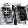 Two open metal compartments of the Premium Hydraulic Tipper Car Trailer 4200kg ATM 16.4×6.6FT (5x2M) Deck Size show a battery with cables on the left and mechanical components, wires, and fluid reservoirs on the right. The interior features a reflective lining.